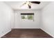 Neutral bedroom with dark floors, ceiling fan, and a window with outside views at 3644 W Maryland Ave, Phoenix, AZ 85019