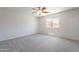 Empty carpeted bedroom with a window providing natural light and a ceiling fan at 37053 W Amalfi Ave, Maricopa, AZ 85138