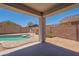Backyard pool with clear water and desert landscaping seen from covered patio at 37053 W Amalfi Ave, Maricopa, AZ 85138