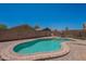 Kidney-bean shaped pool in fenced yard with desert landscaping at 37053 W Amalfi Ave, Maricopa, AZ 85138