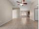 Bright living room with tile flooring, neutral paint, ceiling fan, and view into the kitchen at 43875 W Baker Dr, Maricopa, AZ 85138