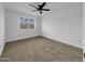This bedroom features neutral walls and carpet, a ceiling fan and a view to the outdoors through the window at 4416 E Riverside St, Phoenix, AZ 85040