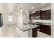 Open kitchen with a large granite island, dark wood cabinets, stainless steel appliances, and plenty of counter space at 5626 W Rainwater Dr, Laveen, AZ 85339