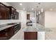 Modern kitchen features dark wood cabinetry, granite countertops, stainless appliances, and a large island with a sink at 5626 W Rainwater Dr, Laveen, AZ 85339