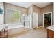 Primary bathroom with soaking tub, glass block window, and walk-in shower at 8417 W Northview Ave, Glendale, AZ 85305