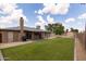 Expansive backyard with green lawn, covered patio, brick chimney, and storage shed at 929 W Knowles Cir, Mesa, AZ 85210