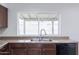 Bright kitchen includes a double sink, wood cabinets, and modern appliances beneath a sunny window at 929 W Knowles Cir, Mesa, AZ 85210