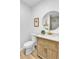 Bathroom featuring a wood vanity, round mirror, and a white toilet at 10844 N 37Th Way, Phoenix, AZ 85028