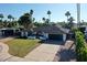 Beautiful single-story home featuring a well-maintained lawn, black garage door, mature trees, and desert landscaping at 10844 N 37Th Way, Phoenix, AZ 85028