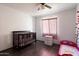 Cozy Bedroom with dark wood floors, a ceiling fan, a baby crib, and a toddler bed at 12410 W Flores Dr, El Mirage, AZ 85335