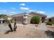 Single-story home with desert landscaping featuring mature plantings and an attached two-car garage in a quiet neighborhood at 12410 W Flores Dr, El Mirage, AZ 85335