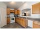 Practical kitchen with wood cabinets, white appliances, gray tile flooring, and an open serving bar at 12410 W Flores Dr, El Mirage, AZ 85335