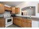 Well-appointed kitchen featuring wood cabinets, white appliances, gray tile flooring, and an open serving bar at 12410 W Flores Dr, El Mirage, AZ 85335