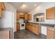 Functional kitchen featuring wood cabinets, white appliances, and gray tile flooring with an open serving bar at 12410 W Flores Dr, El Mirage, AZ 85335