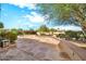 View of the back patio featuring a patterned concrete patio, stone wall and mature landscaping at 15101 W Waterford Dr, Surprise, AZ 85374