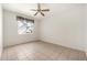 Simple bedroom featuring tile floors, ceiling fan, and a bright window at 15101 W Waterford Dr, Surprise, AZ 85374