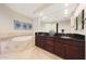 Primary bathroom features a soaking tub, dual sinks, and dark cabinets at 15802 N 71St St # 552, Scottsdale, AZ 85254