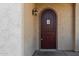 Close up of the rich wood front door with sidelight, decorative sconce and textured stucco wall at 16846 N 49Th Way, Scottsdale, AZ 85254