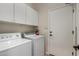 A laundry room with white washer and dryer and overhead cabinets at 16846 N 49Th Way, Scottsdale, AZ 85254