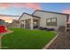 Inviting backyard with lush artificial grass, a covered patio, and cozy lounging area with a fire pit at 17140 W Running Deer Trl, Surprise, AZ 85387