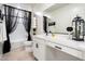 Bright bathroom with white vanity, black accents, shower with curtain and modern fixtures at 17140 W Running Deer Trl, Surprise, AZ 85387