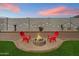 Backyard featuring cozy fire pit with seating, artificial turf, rock landscaping and privacy wall at 17140 W Running Deer Trl, Surprise, AZ 85387