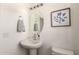 Clean, modern powder room with pedestal sink, oval mirror, and stylish botanical art at 1879 W 23Rd Ave, Apache Junction, AZ 85120