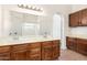 Bathroom with double sinks, wood cabinets, neutral tile floors and a large mirror at 18805 N 49Th Dr, Glendale, AZ 85308