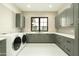 Well-lit laundry room featuring a modern washer/dryer and beautiful gray cabinets with stylish countertops and tiled backsplash at 2315 E Mine Creek Rd, Phoenix, AZ 85024