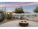 Outdoor living space showcasing a fire pit and a unique desert mural on the back wall at 2487 S Conestoga Rd, Apache Junction, AZ 85119