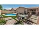 Inviting backyard featuring a sparkling pool, outdoor dining set, and well-maintained artificial turf at 2813 N 107Th Dr, Avondale, AZ 85392