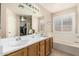 Bright bathroom with double sink vanity, bathtub, and window with shutters at 2813 N 107Th Dr, Avondale, AZ 85392