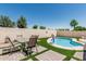 Inviting pool area with a patio table set, synthetic grass, and privacy wall creating a perfect backyard oasis at 2813 N 107Th Dr, Avondale, AZ 85392
