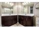 Bathroom featuring double vanity with dark wood cabinets, white countertops, mirrors, and tiled floors at 29819 W Whitton Ave, Buckeye, AZ 85396