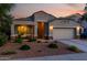 Well-maintained home featuring desert landscaping, a two-car garage, and a welcoming entrance illuminated by warm exterior lighting at 29819 W Whitton Ave, Buckeye, AZ 85396