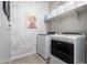 Functional laundry room with modern washer and dryer, floral wallpaper, and ample shelving at 29819 W Whitton Ave, Buckeye, AZ 85396