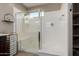 Bright bathroom shower featuring glass doors, white walls, shower head, and tiled floors at 29819 W Whitton Ave, Buckeye, AZ 85396