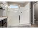 Bright bathroom shower featuring glass doors, white walls, shower head, and tiled floors at 29819 W Whitton Ave, Buckeye, AZ 85396