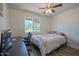 Bright bedroom featuring wood floors, a ceiling fan, a work space, and a sunlit window with views of palm trees at 310 E Fremont Dr, Tempe, AZ 85282