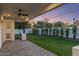 Covered patio overlooks a manicured backyard with lush lawn, privacy plants, and a white brick perimeter wall at 3848 E Fairmount Ave, Phoenix, AZ 85018