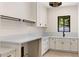 Bright laundry room with white cabinetry, quartz countertops, black hardware, and a window overlooking greenery at 3848 E Fairmount Ave, Phoenix, AZ 85018