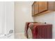 Laundry room with red washer and dryer, overhead storage cabinets, and tile floor at 3900 E Baseline Rd # 166, Phoenix, AZ 85042