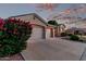 Charming home exterior with a three-car garage and vibrant flowering bushes at dusk at 4215 W Hackamore Dr, Phoenix, AZ 85083