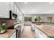 Well-lit kitchen with stainless steel appliances, white cabinets and stone countertops with a beautiful backyard view at 4215 W Hackamore Dr, Phoenix, AZ 85083