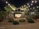 Backyard with stone fountain, rock landscaping, palm trees, paver patio and string lights at night at 4426 E Leroy St, Gilbert, AZ 85295