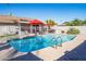 Inviting backyard with sparkling pool, red umbrellas, and shaded patio space for relaxing on a sunny day at 501 W Jasper Dr, Chandler, AZ 85225