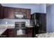 Modern kitchen with granite counters, stainless steel appliances, and dark wood cabinets at 6999 S Blue Hills Dr, Buckeye, AZ 85326