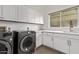 Laundry room with gray front-loading machines, white cabinets, and neutral countertop at 7376 E Via Estrella Ave, Scottsdale, AZ 85258