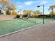 Community tennis court surrounded by mature trees and gravel, perfect for an active lifestyle at 7376 E Via Estrella Ave, Scottsdale, AZ 85258