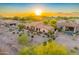 Aerial view of home in desert neighborhood with lush landscaping, golf course, and sunset at 8139 E Club Village Dr, Gold Canyon, AZ 85118